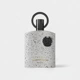 Perfume bottle with speckled design and black cap on a white background